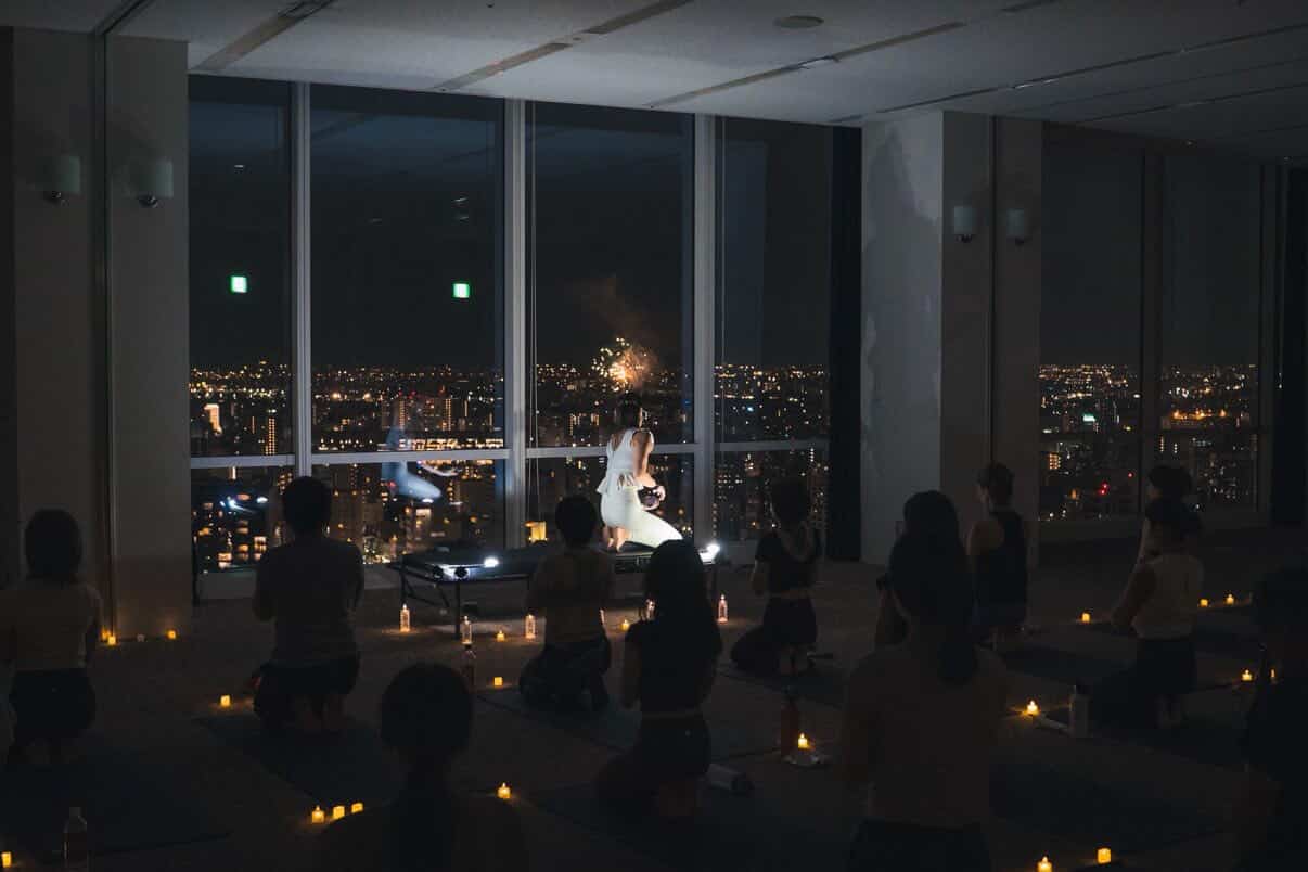 前回開催の様子 - 夜景を背景にヨガを行う参加者の皆さん